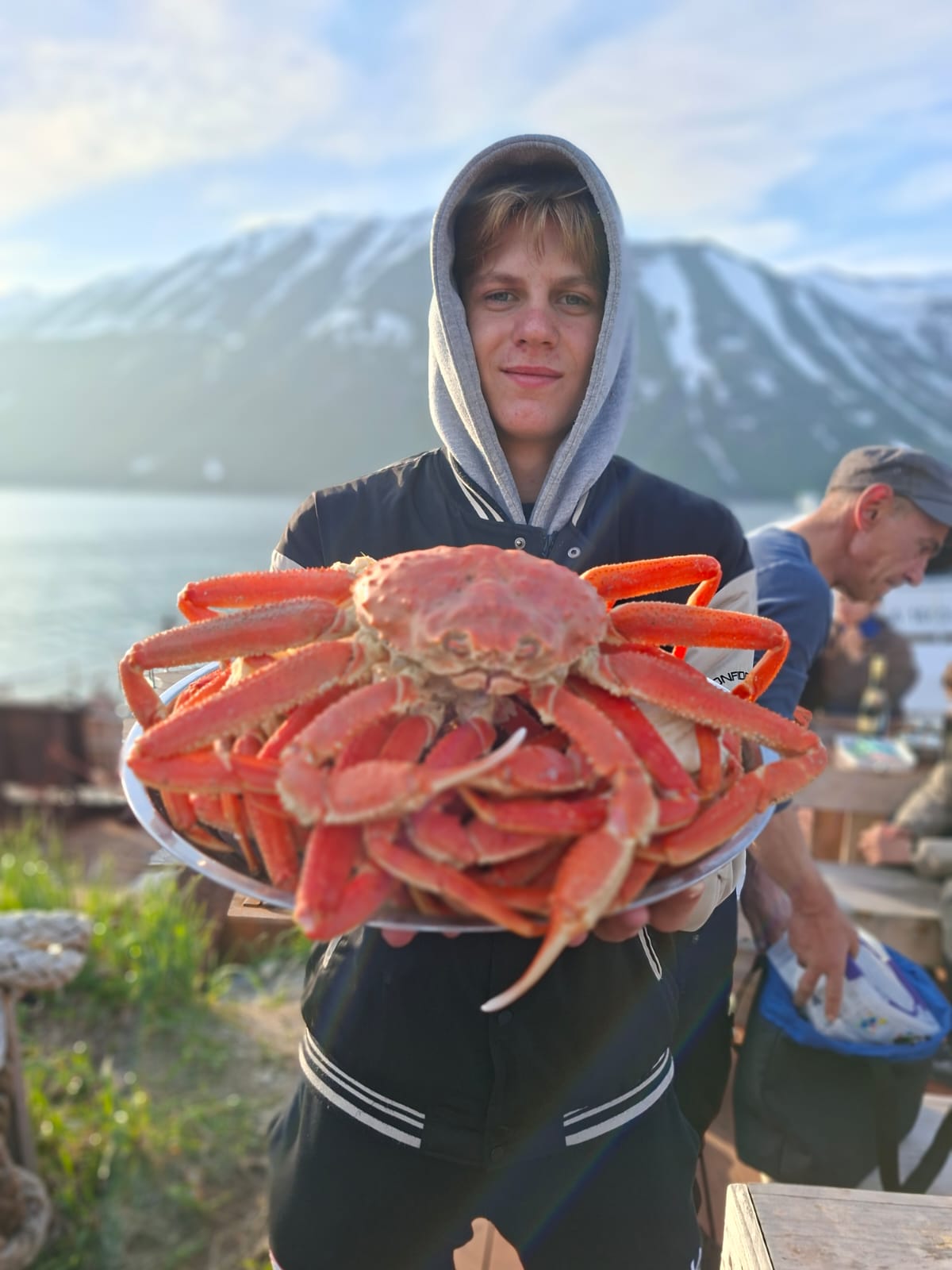 Гость держит поднос с приготовленными крабами после морского выхода на Камчатке