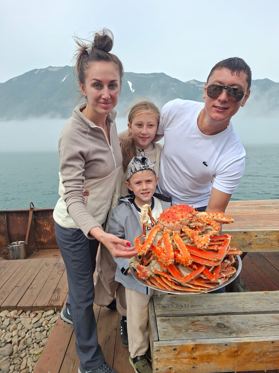 Семья с большим блюдом свежесваренного камчатского краба на береговой остановке